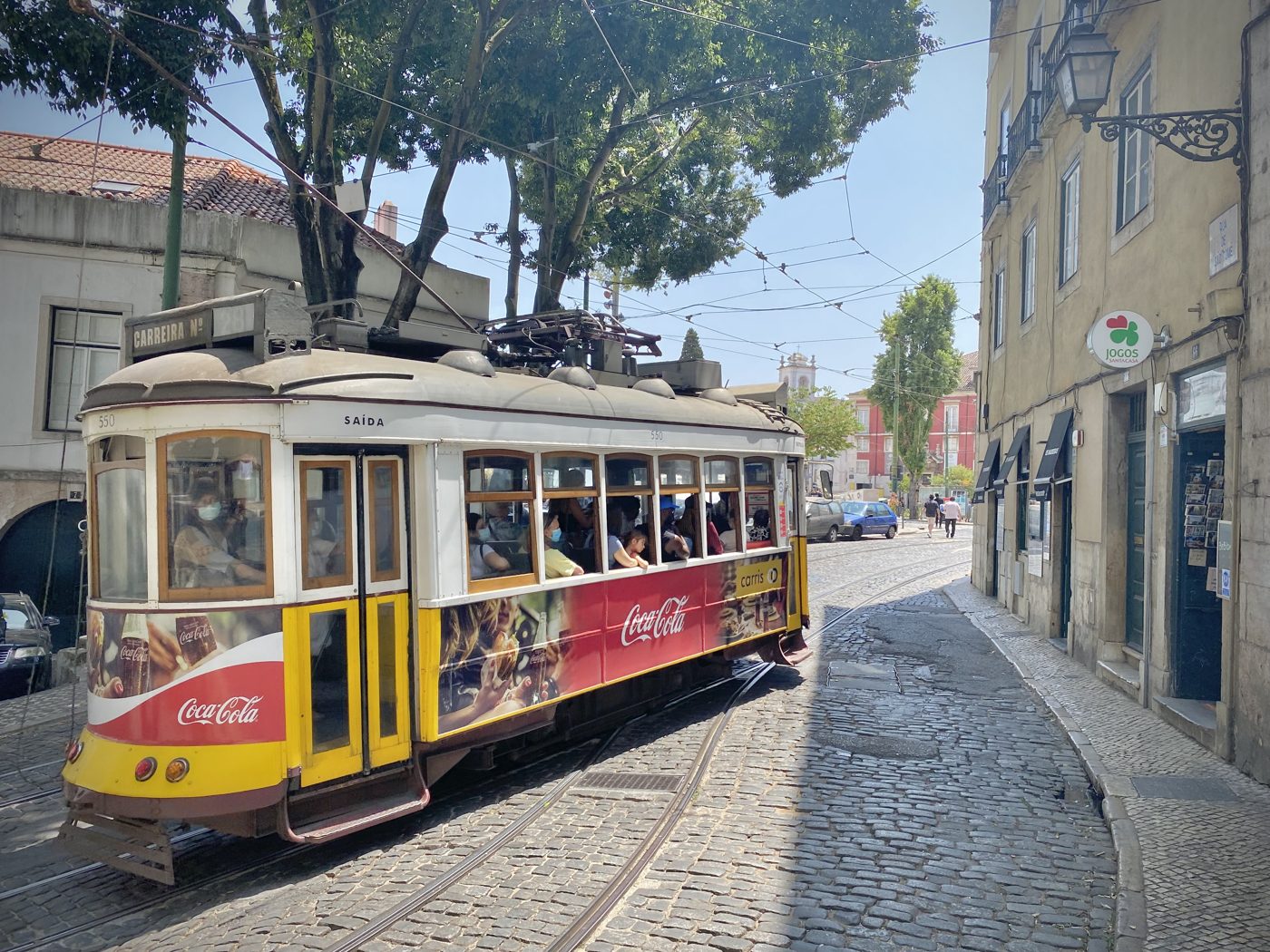 Historic yellow tram on a cobbled street in Alfama, Lisbon